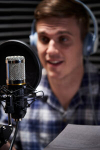Man reading document in front of a microphone in a sound booth